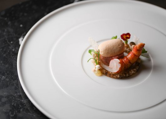 Lampl Stube: il nostro ristorante a Castelrotto Piatto gourmet con gamberi, crema e fiori commestibili su piatto bianco