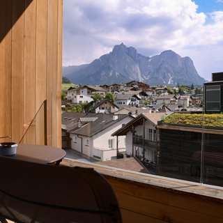 Lampl Stube: il nostro ristorante a Castelrotto Balcone con tavolo e sedie con vista su villaggio di montagna e cime rocciose