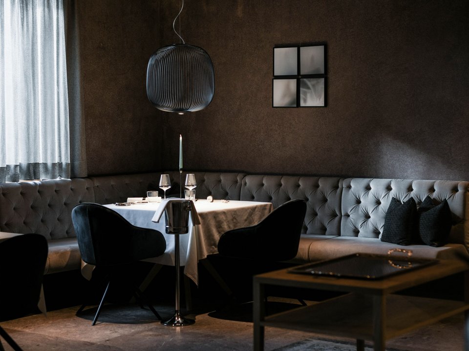 Hotel con spa a Castelrotto Zona pranzo accogliente e scura con tavolo, sedie e divano