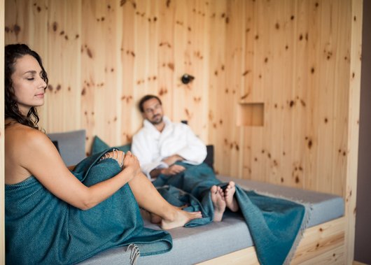 4-Sterne-Hotel Lamm am Fuße der Seiser Alm Paar entspannt in einer Sauna, umgeben von Holzvertäfelung