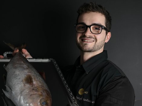 4-Sterne-Hotel Lamm am Fuße der Seiser Alm Mann mit Brille hält einen großen Fisch auf einem Tablett