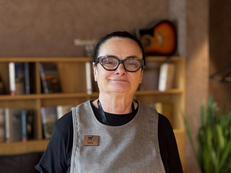 4-Sterne-Hotel Lamm am Fuße der Seiser Alm Mitarbeiterin mit Brille und Schürze vor einem Bücherregal