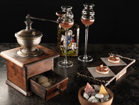 Useful info for your hotel in South Tyrol Vintage coffee grinder with liqueur glasses, bottle, pastries and a bowl of sweets