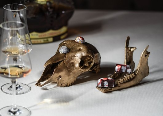 Gourmet restaurant in South Tyrol: Lampl Stube Golden animal skull and jaw with chocolates on white tablecloth