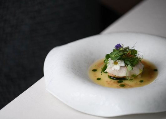 Gourmet restaurant in South Tyrol: Lampl Stube Fine dish with flowers and green herbs on a white bowl