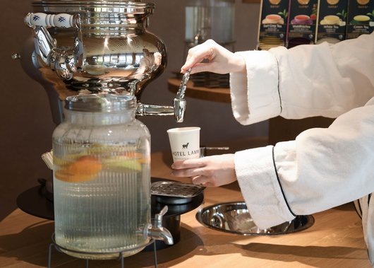 Hotel con spa a Castelrotto Persona che versa tè da un grande samovar d'argento in una tazza