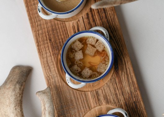 Gourmet restaurant in South Tyrol: Lampl Stube Three soups in bowls on wooden board with deer antlers