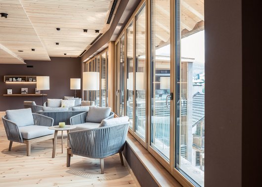 4-Sterne-Hotel Lamm am Fuße der Seiser Alm Moderne Lounge mit grauen Sesseln und großen Fensterfronten