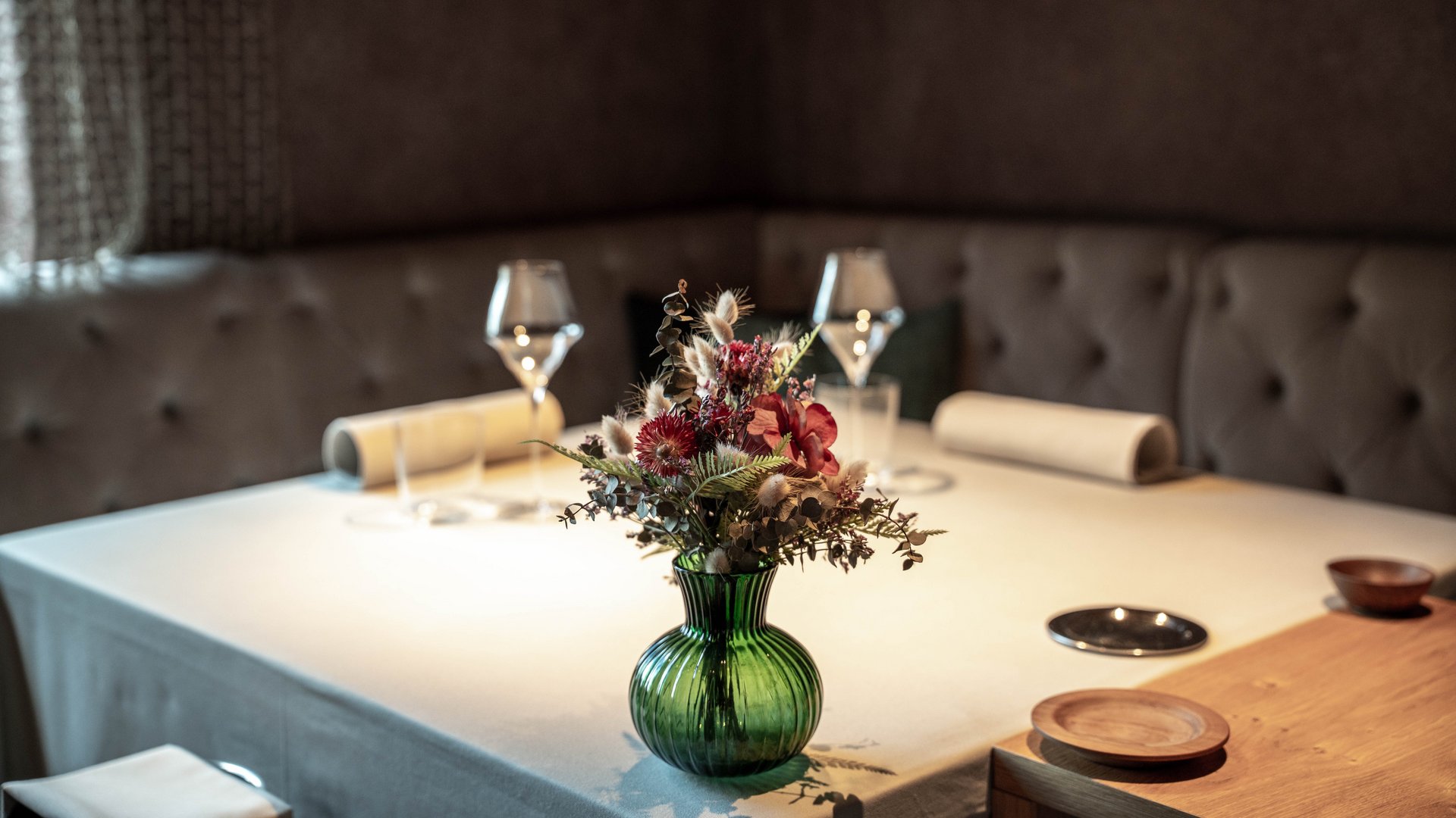 Useful info for your hotel in South Tyrol Table with green flower vase and wine glasses in cozy restaurant