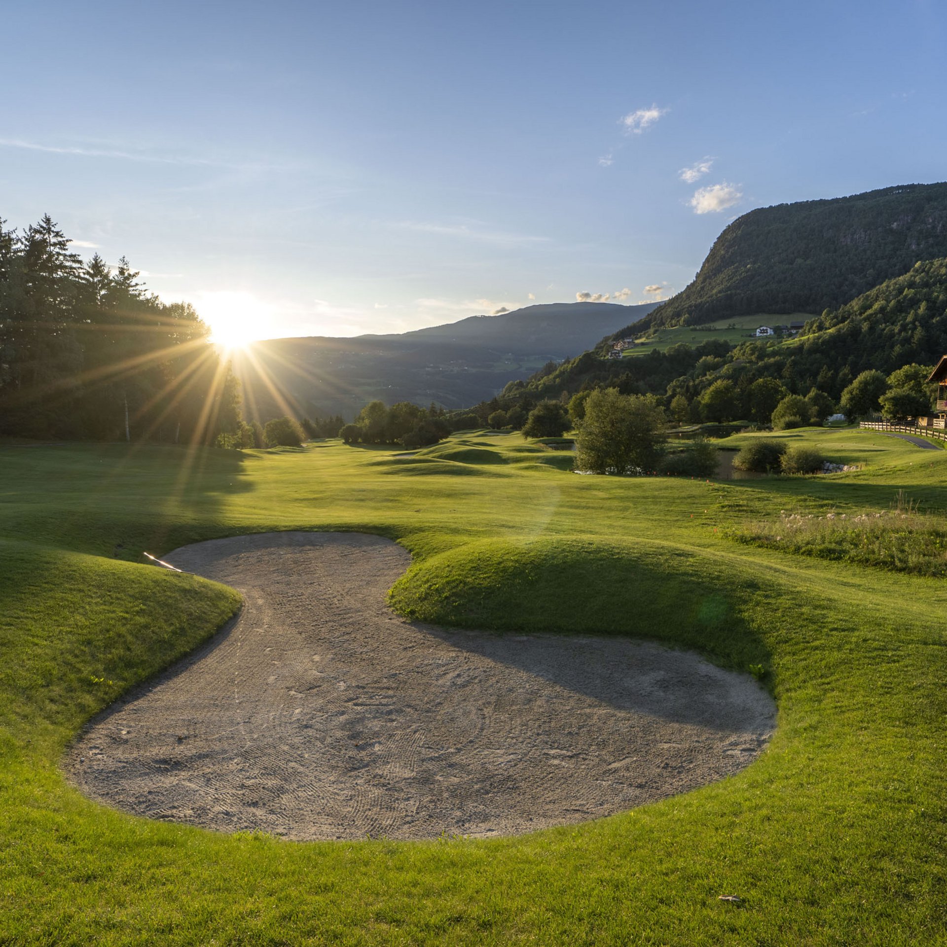 4-Sterne-Hotel Lamm am Fuße der Seiser Alm Golfplatz mit Sandbunker und Sonnenuntergang in den Bergen