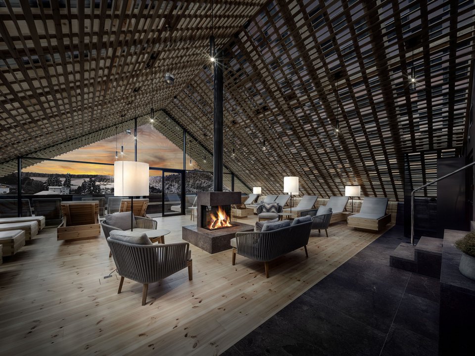 A winter holiday on Alpe di Siusi/Seiser Alm: Hotel Lamm Cozy lounge with fireplace and wooden furniture in a modern attic space