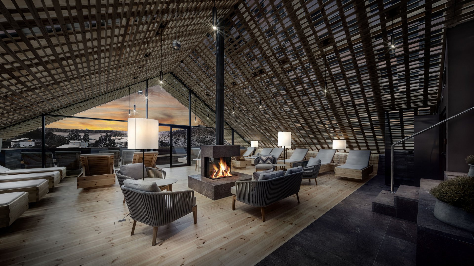 Hotel con spa a Castelrotto Lounge accogliente con camino e mobili in legno in un moderno sottotetto