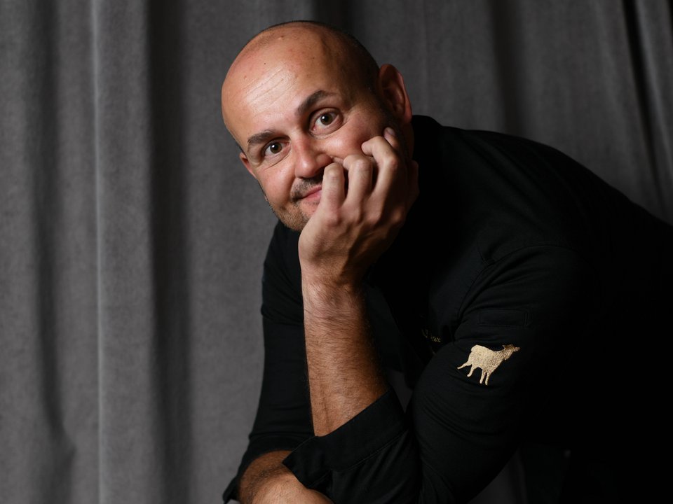 Gourmet restaurant in South Tyrol: Lampl Stube Bald man leaning on a black chair in front of a gray curtain